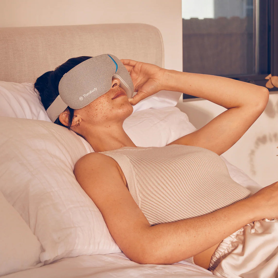 Person wearing a sleep mask in bed, with a blurred background
